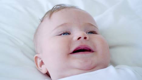 overhead shot of baby boy lying on bed and smiling