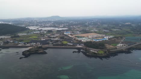 drone aerial view in south korea countryside flying over the ocean and green island small village island jeju island cloudy