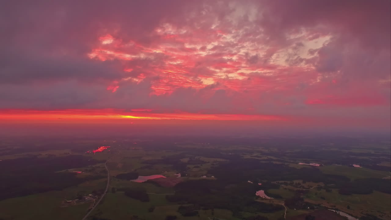 Aerial drone shot over red predawn twilight over small ponds along rural countryside on a cloudy morning