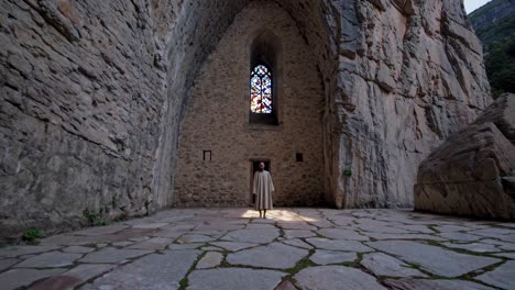 monk standing in the middle of an ancient stone church with colorful stained glass window and stone floor, embracing solitude and spirituality