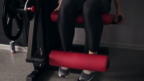 Footage-of-female-legs-working-out-on-front-leg-extension-mashine-at-the-gym.-Indoors-slow-motion.-Endurance-and-concentration.