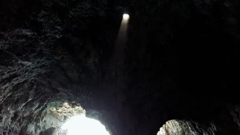 mystical atmosphere inside a sea cave with a ray of light coming down from a hole in the ceiling, vis island, adriatic sea, croatia