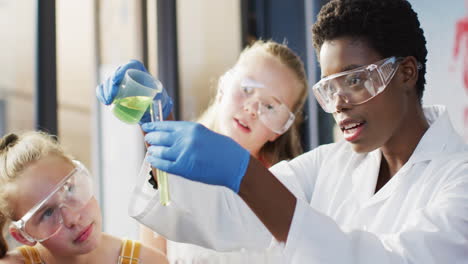 maestra diversa y escolares felices teniendo clase de ciencias en el laboratorio escolar