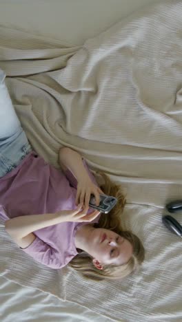 woman lying on bed using smartphone