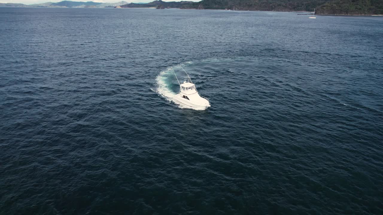 Drone shot with semi orbit and zoom in on a fishing boat creating a trail across the open water.