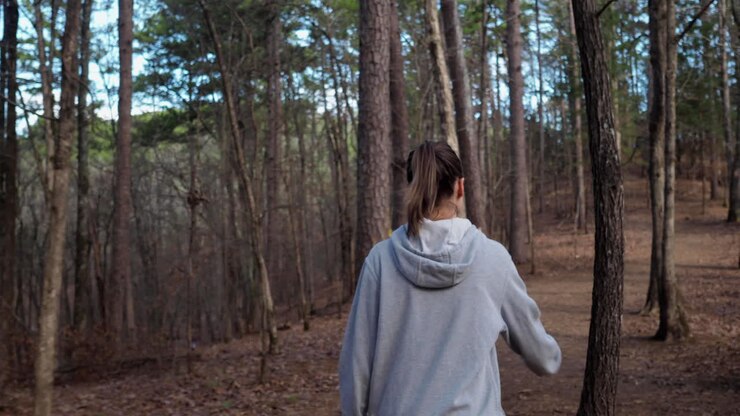 Young woman in grey hoodie walking through the forest of broken bow Oklahoma