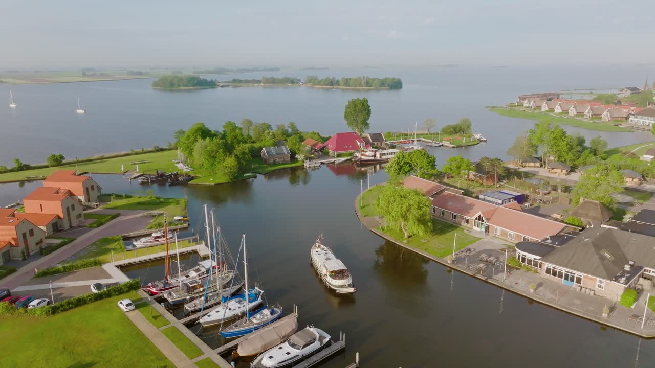 Aerial semi orbit of a Luxemotor boat close to the marina in Heeg, Netherlands, with yachts, houses and waterfront buildings