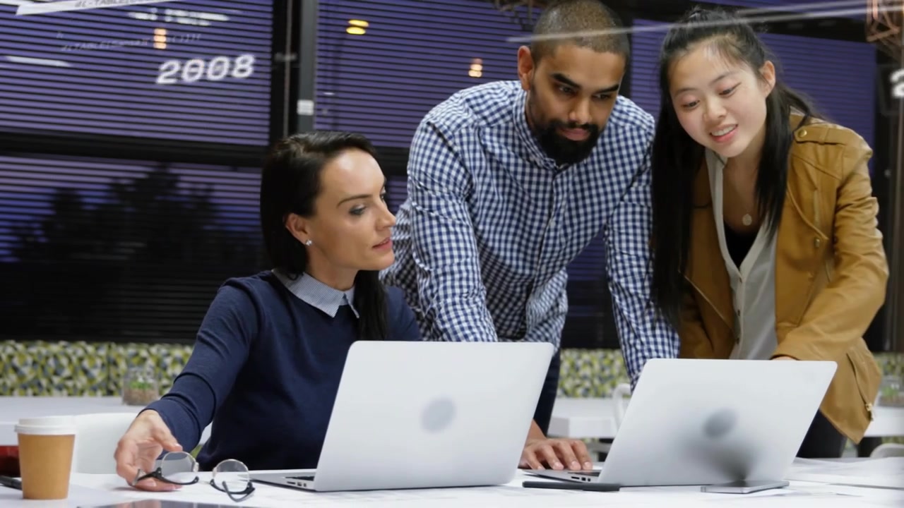 Three professionals reviewing data on laptops, updating timeline charts and adjusting glasses