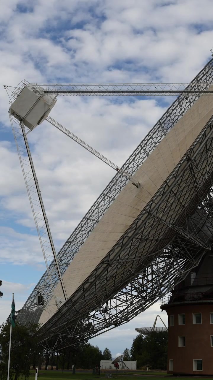 Grande parabola di un radiotelescopio che ruota sotto un cielo nuvoloso