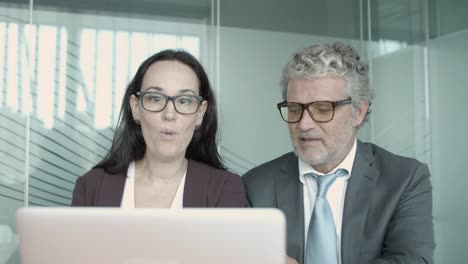 Middle-aged-boss-in-eyeglasses-discussing-with-female-assistant