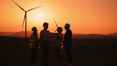 wind farm engineers discussing project at sunset