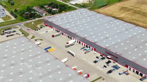 Aerial-view-of-a-semi-trucks-with-cargo-trailers-standing-on-warehouses-ramps-for-loading-unloading-goods-on-the-big-logistics-park-with-loading-hub