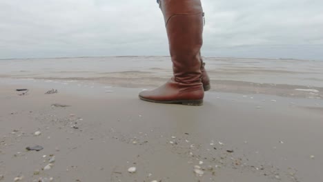 Ein-Mädchen-In-Braunen-Hohen-Stiefeln-Und-Jeans-Geht-Im-Herbst,-November,-An-Der-Ostseeküste-In-Lettland-Spazieren