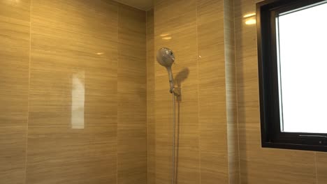 cabeza de ducha blanca simple en el baño con pared de azulejos de granito