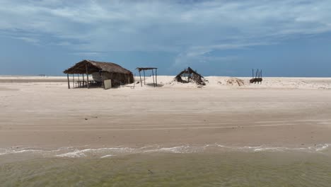 wooden shelter structures at sandy parnaiba riverbank, left track shot