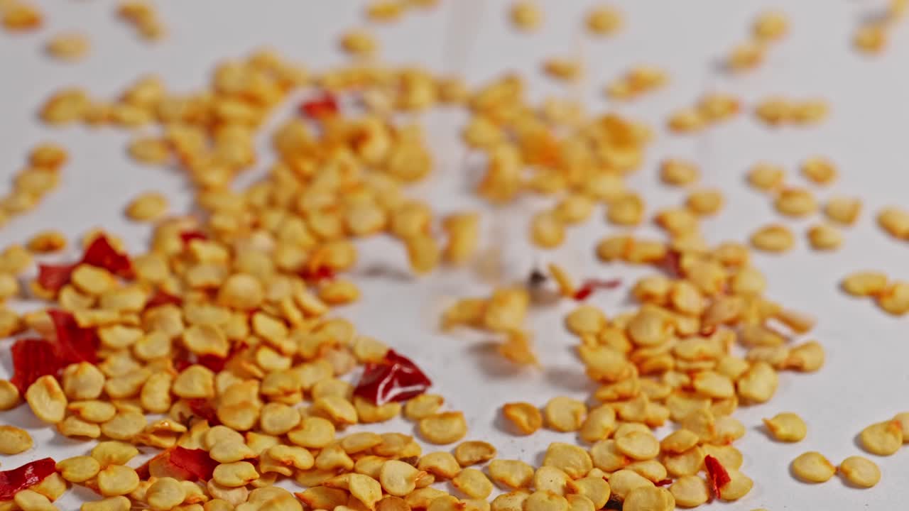 chilli flakes falling on white surface and bouncing, 4k, stable shot
