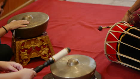 skinned drum and south east asian bonang being struck with mallets during performance of multiple percussive instruments, filmed as close up