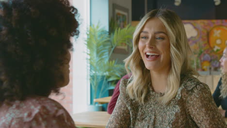 close up of two female friends meeting in coffee shop and talking