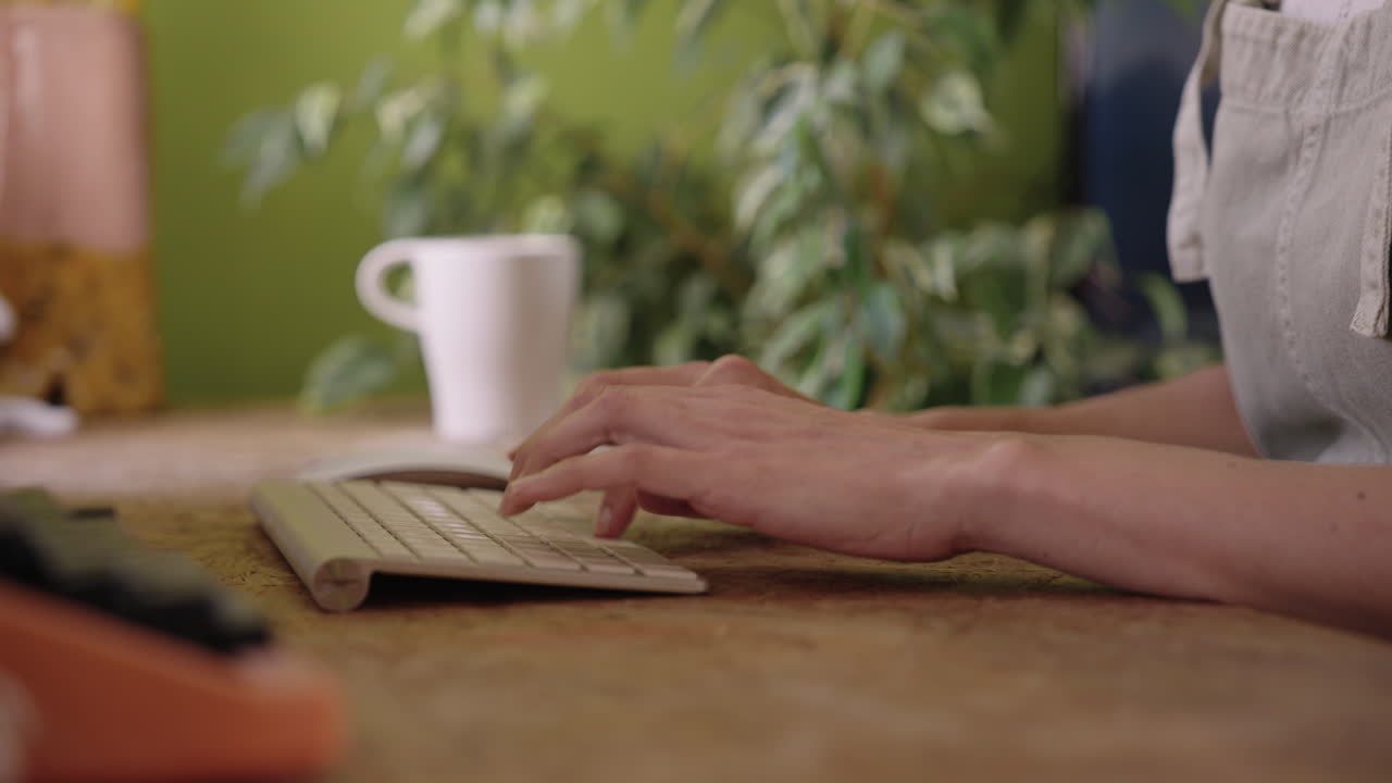 Donna che lavora al computer sulla scrivania di casa con una tazza di caffè. Scena accogliente di home office che mostra uno stile di vita moderno, lavoro da remoto e produttività quotidiana