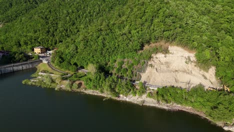 drone image captures excavators and rocks on the sp21 near vernasca on the mignano dam in the arda valley, after landslide on april 22nd, mountain forest surrounding, drone shot, real time