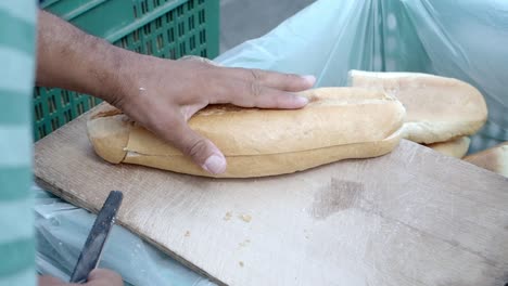 person cutting a loaf of bread on a cutting board