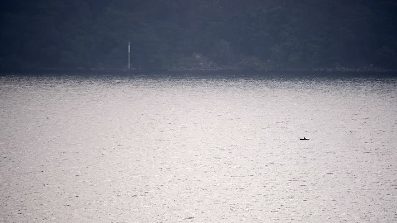 호수의 고요한 샷과 멀리서 낚시를 할 수 있는 남자