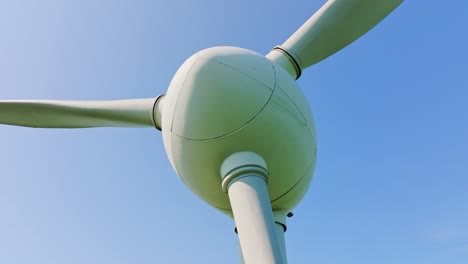 still wind turbine under clear blue sky as drone ascends and rotates smoothly