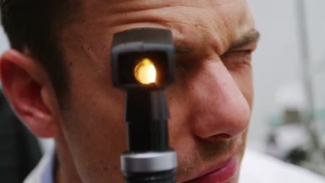 primer plano del optometrista mirando a través del oftalmoscopio