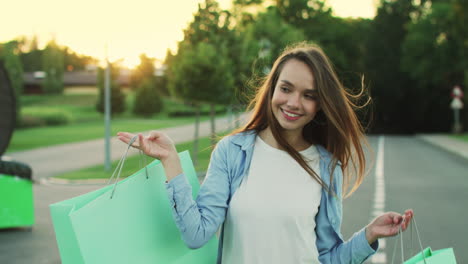 mujer sonriente con una bolsa de compras caminando por la calle en el parque de la ciudad. mujer feliz