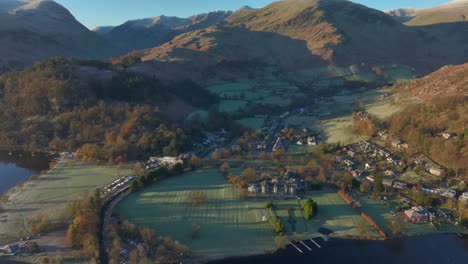 Lakeside-village-surrounded-by-mountains-bathed-in-autumn-sunrise-sunshine