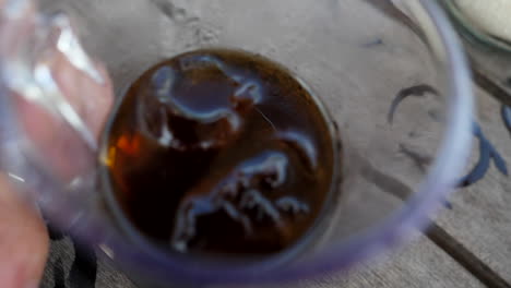 primer plano de una mano sosteniendo una bebida helada mientras entra y sale de la taza