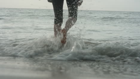 pretty blonde girl walking barefoot into the waves at the beach, bleik, lofoten islands, norway, beautiful sunset atmosphere