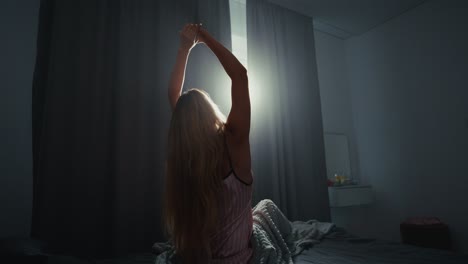 mujer estirándose en la cama al amanecer