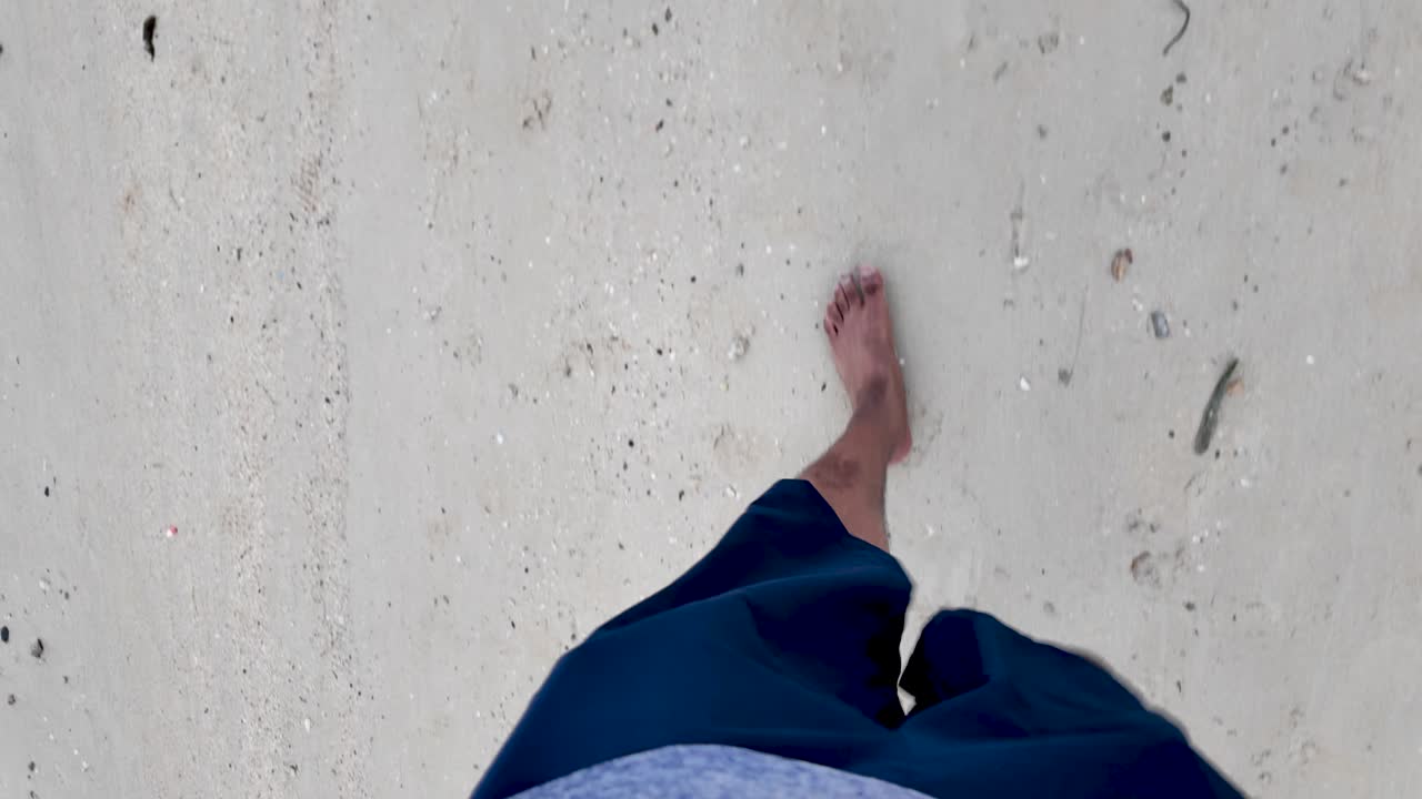 A peaceful point-of-view image showcasing bare feet walking on a sandy beach, conveying a sense of relaxation and tranquility.