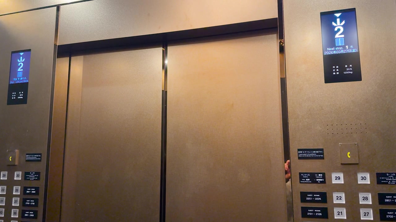 Static shot of modern elevator doors and digital display showing floor numbers descending downwards.