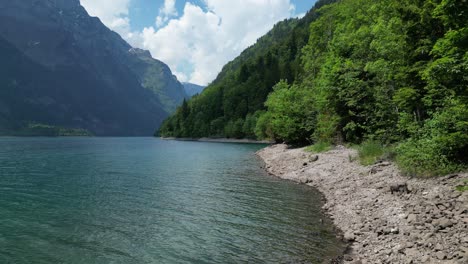 picturesque klontalersee lake shore where calm waters meet rocks and lush green vegetation