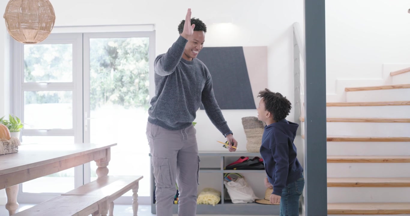 African American man and child placing tape on entry post, man marking with pencil tracking growth