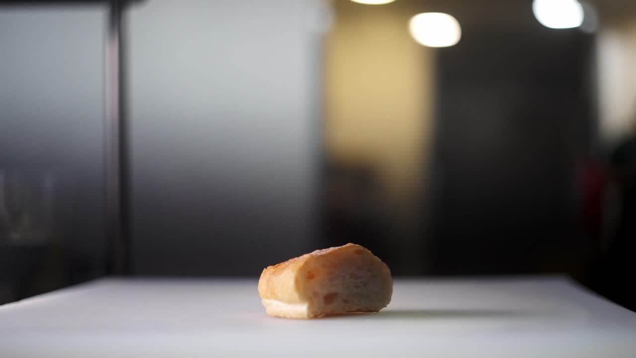 Cinematic and creative close up view of a hand crushing and smashing a loaf of bread baguette and crumbles flying all over in slow motion in a restaurant cuisine