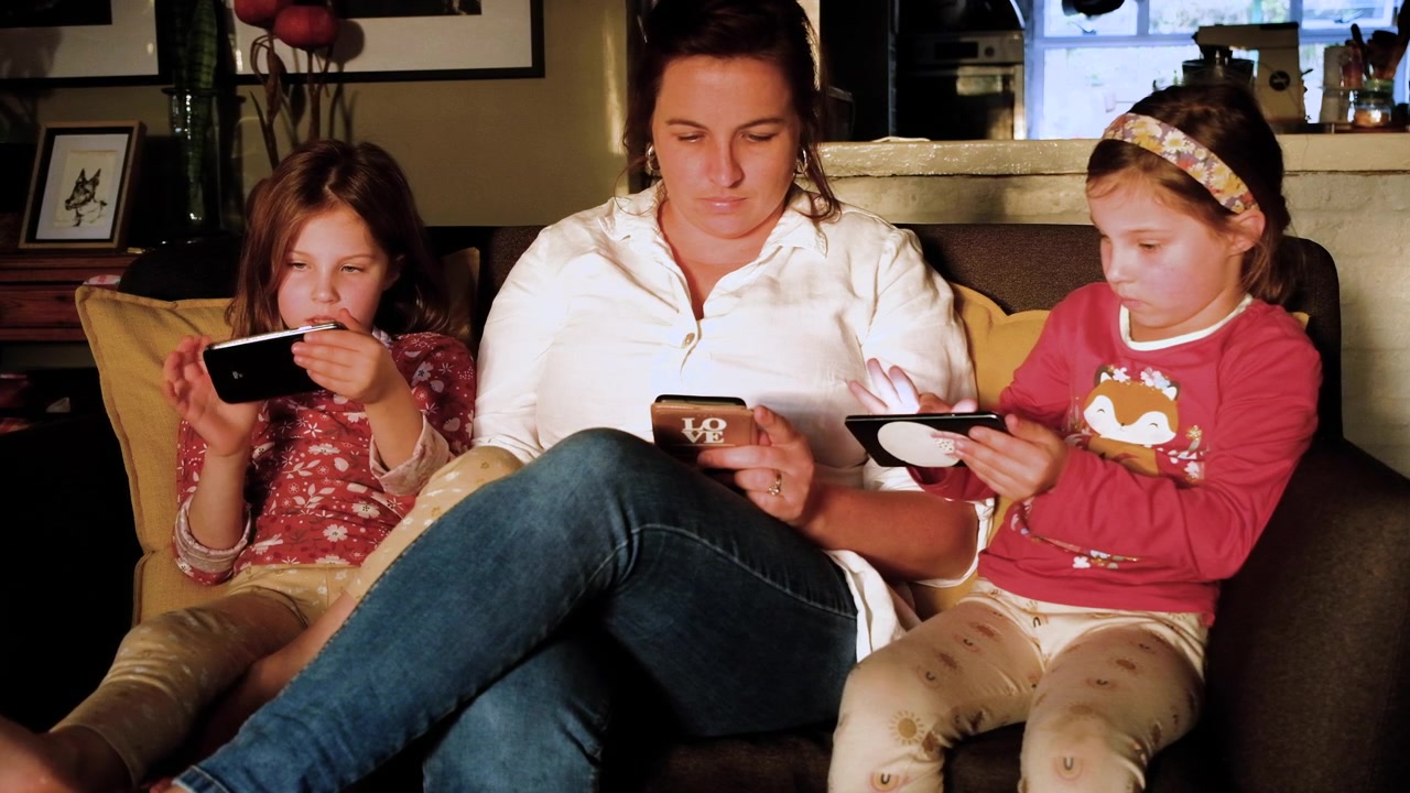 Mom monitoring her twin daughters' screen time, responsible parenting
