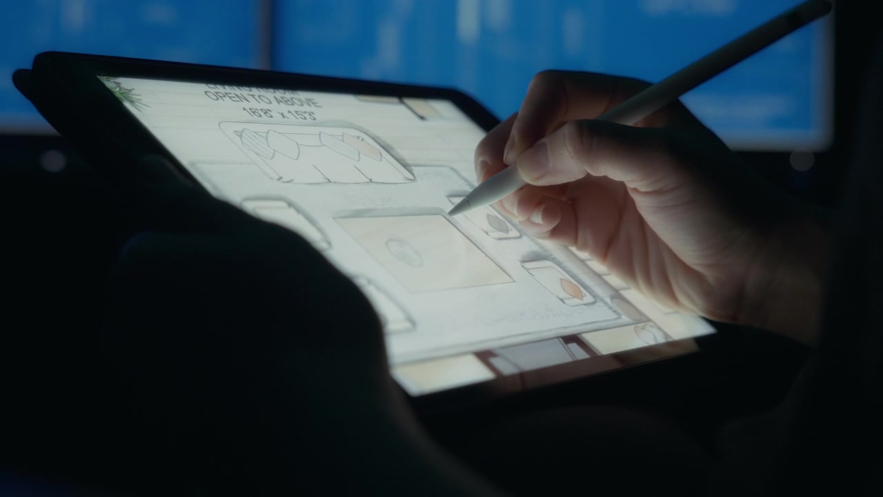 Designer dessinant sur le plan d'une maison à l'aide d'une tablette