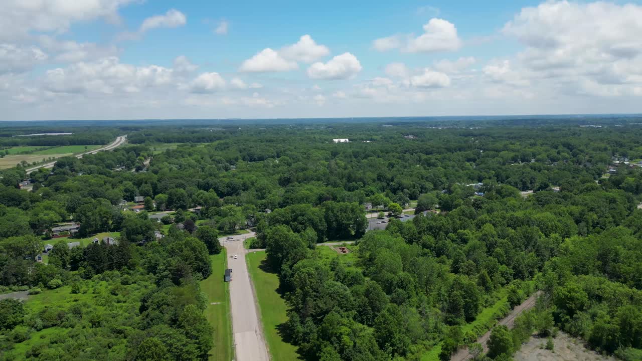Stunning aerial footage of a vast green landscape with roads and scattered homes. Perfect for projects on nature, real estate, and urban planning. Highlights expansive greenery and open skies.