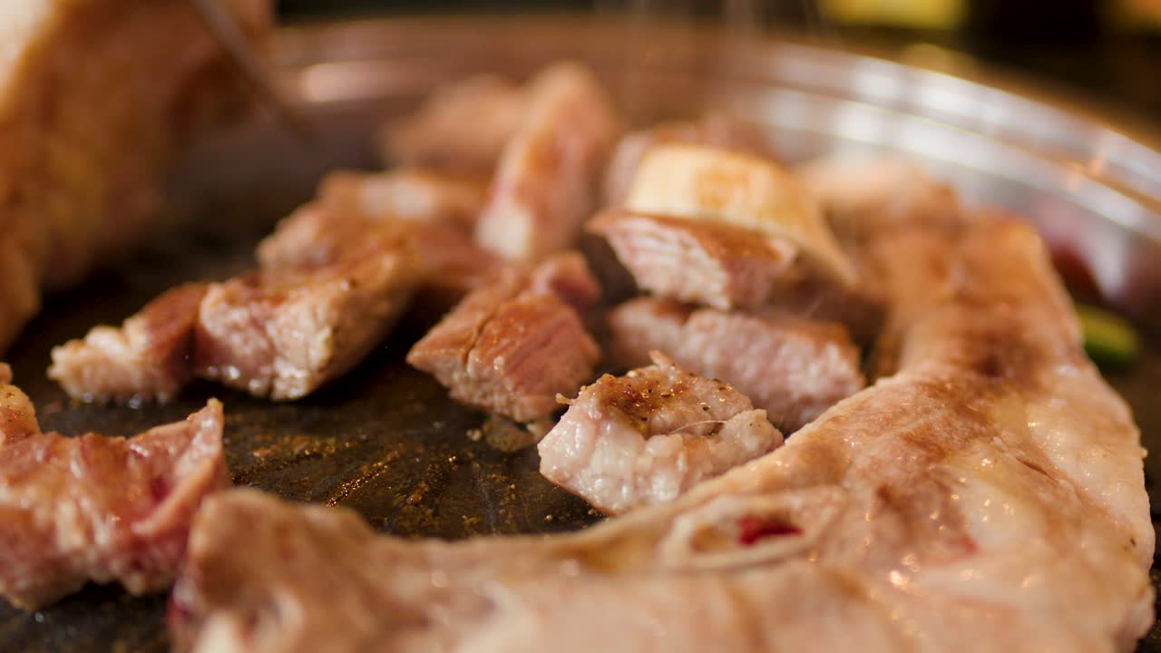 Juicy pork slices grilling on hot plate, macro view, warm lighting, shallow depth, gentle zoom