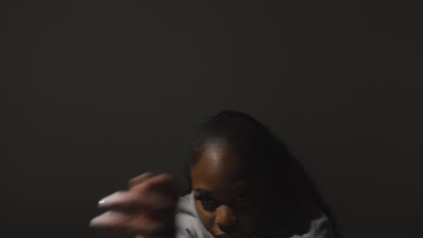 studio portrait shot of young woman wearing hoodie dancing with low key lighting against grey background 11