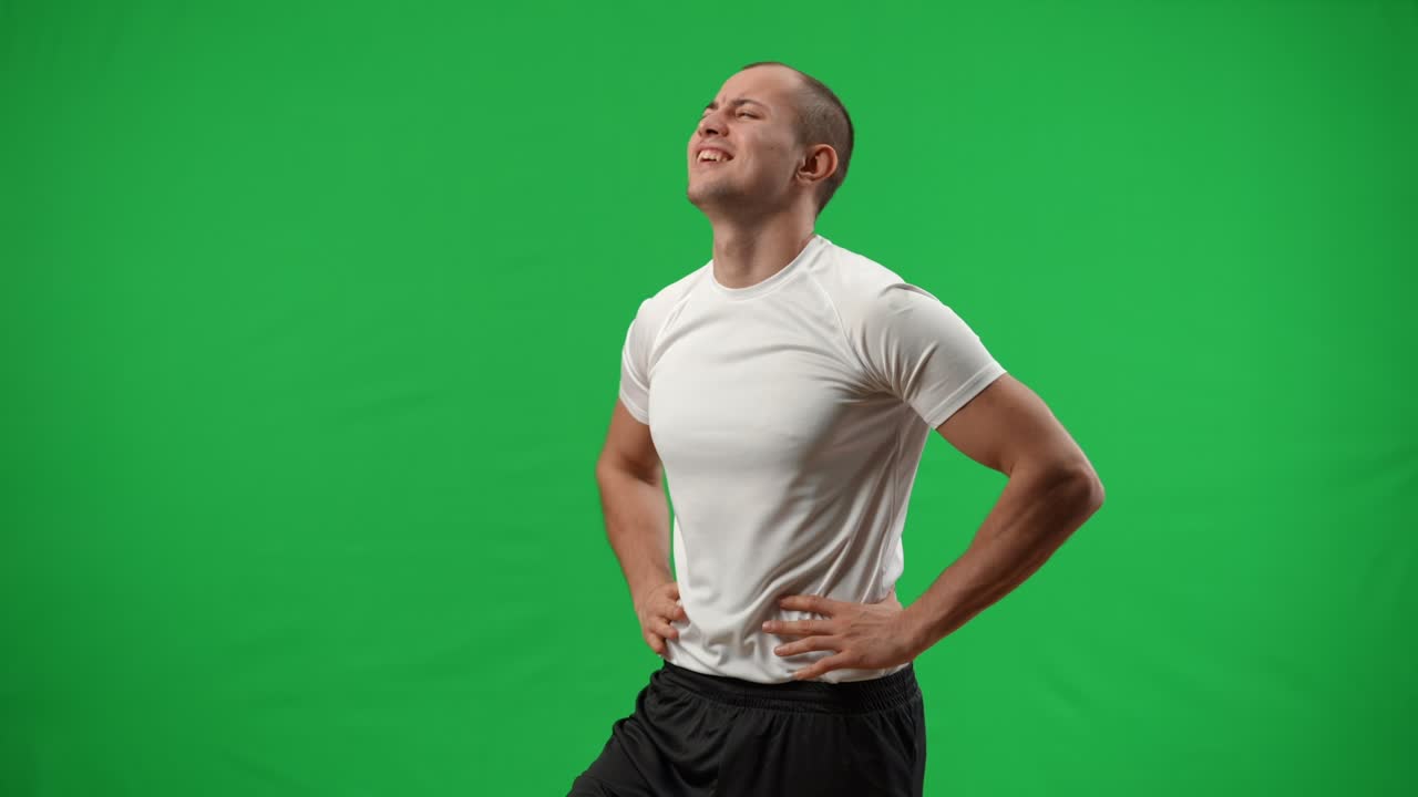 medio tiro satisfecho jugador de fútbol caucásico poniendo la pelota abajo gestando fuerza en la plantilla de fondo chromakey. guapo deportista exitoso mirando lejos regocijándose meta en la pantalla verde.
