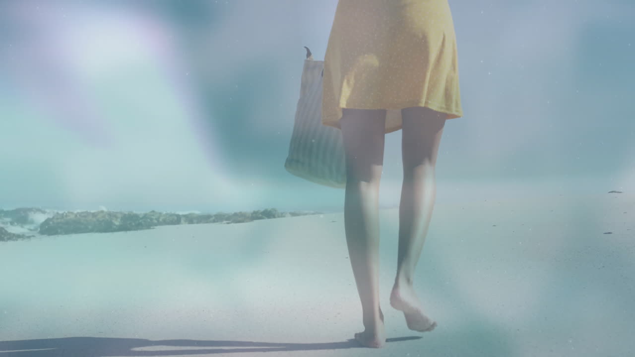 Walking on beach, woman in yellow dress carrying striped bag, enjoying animation