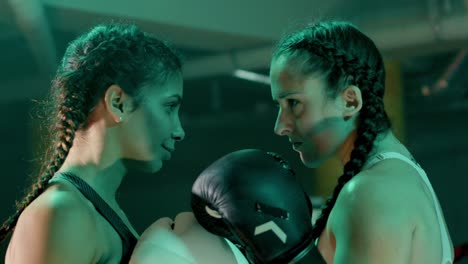 dos boxeadoras preparándose para pelear, de pie cara a cara y manteniendo un intenso contacto visual entre sí