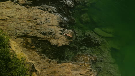 person relaxing on rocks by the ocean