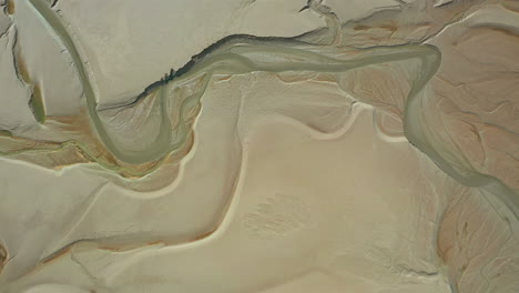 Aerial-top-down-view-over-the-sand-on-a-costal-bay,-showing-the-contour-pattens-at-low-tide