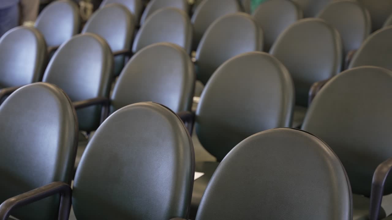 fila de sillas elegantes y negras con respaldos curvos y reposabrazos dispuestos cuidadosamente en un lugar, posiblemente para un evento o ceremonia de asientos
