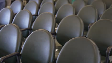 row of sleek, black chairs with curved backs and armrests arranged neatly in a venue, possibly for an event or ceremony seating arrangement